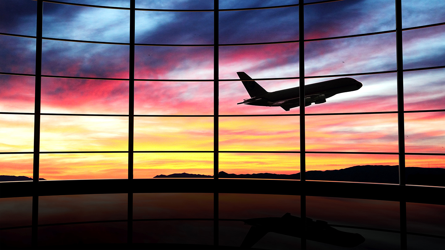 Airplane takes off in front of airport at sunset