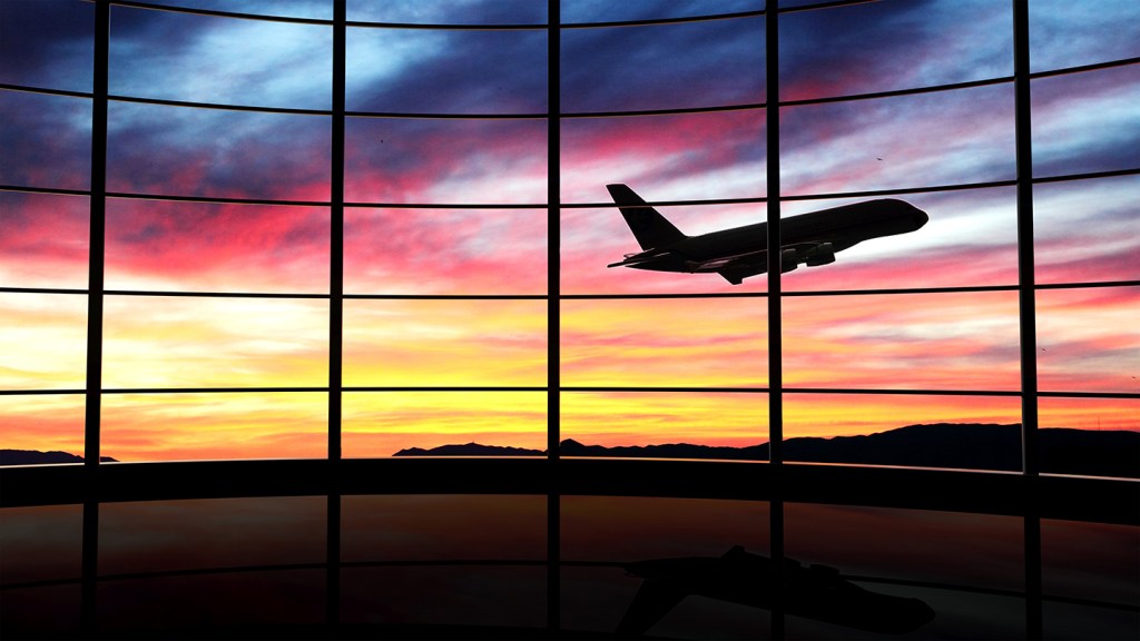 Airplane takes off in front of airport at sunset
